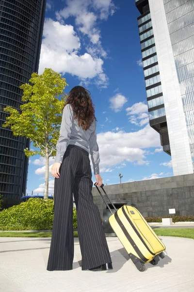 Businesswoman with suitcase and business building — Stock Photo, Image