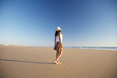 Side woman with hat walking at beach clipart