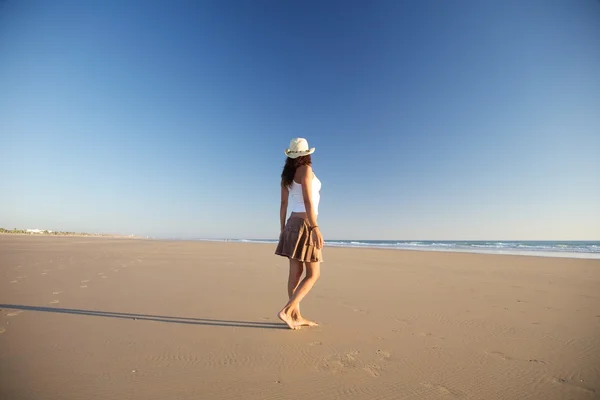 Mulher lateral com chapéu andando na praia — Fotografia de Stock