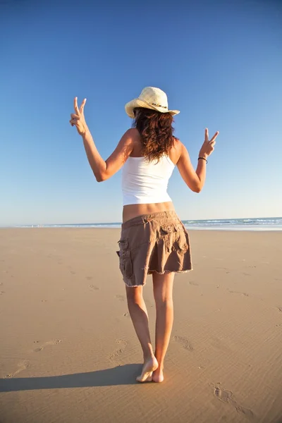 Mulher vencedora com chapéu andando na praia — Fotografia de Stock