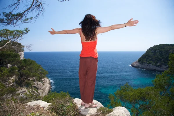 Žena na vrcholu útesu s pozdravem — Stock fotografie