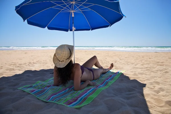 Frau legt sich unter Sonnenschirm — Stockfoto