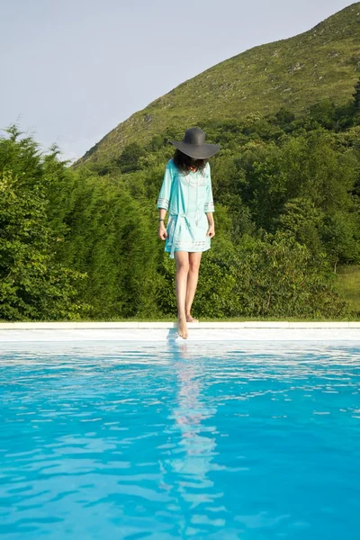 Woman test water on swimming pool border — Stock Photo, Image