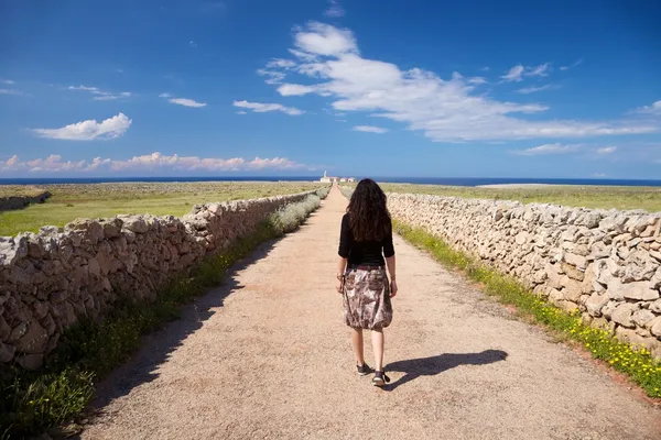 Woman walking rural road to lighthouse — Stock Photo, Image