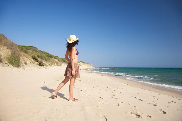 Donna laterale con cappello passeggiando sulla spiaggia — Foto Stock