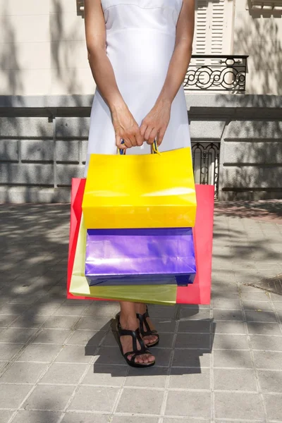 Blanco vestido manos mujer sosteniendo bolsas de compras — Foto de Stock