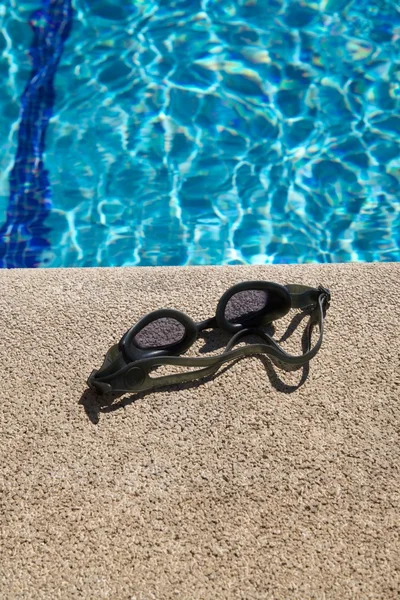 Goggles on curb of swimming pool — Stock Photo, Image
