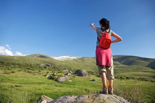 Mochila roja mujer señalando la montaña Gredos —  Fotos de Stock