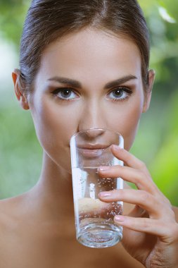 Beautiful young girl drinks water from glass outdoor clipart