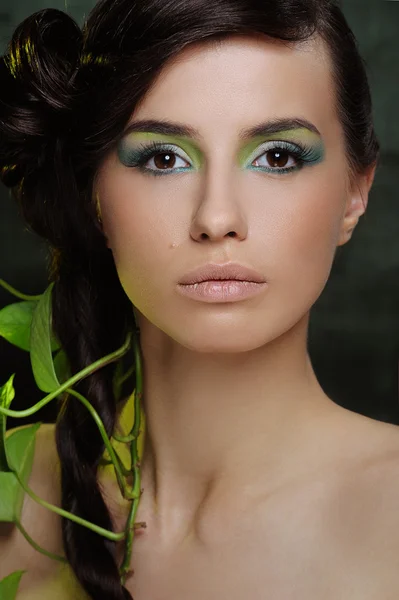Mulher bonita com verde compõem e alguma folha em seu cabelo — Fotografia de Stock