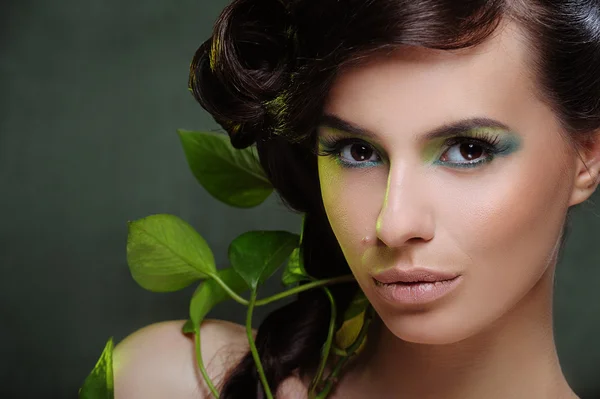 Hermosa mujer con maquillaje verde y algo de hoja en el pelo —  Fotos de Stock