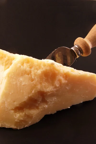 Still life of parmesan cheese with a knife on a black background — Stock Photo, Image