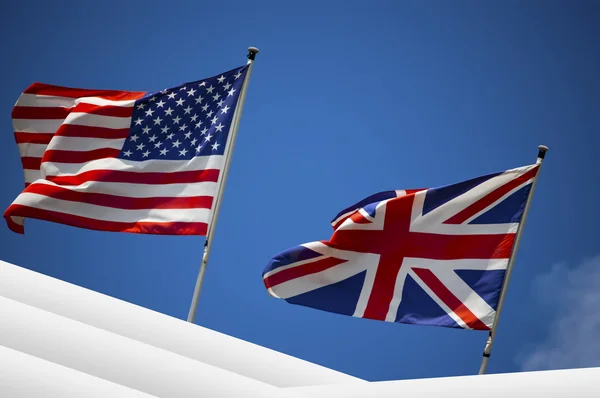 Bandeiras dos EUA e do Reino Unido no céu azul — Fotografia de Stock