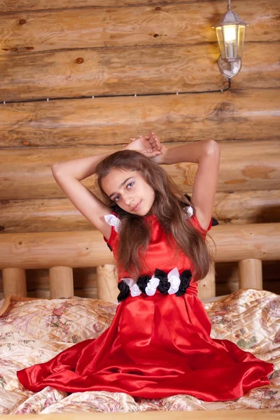 Chica en vestido rojo español sentado en la cama —  Fotos de Stock