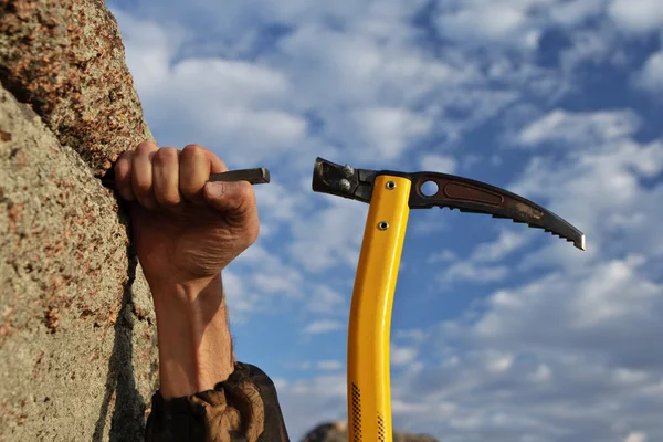 Mãos pedra-alpinista martelando em gancho na rocha — Fotografia de Stock