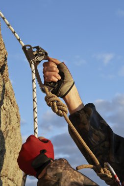 Hands of climber I work with equipment on rock. clipart