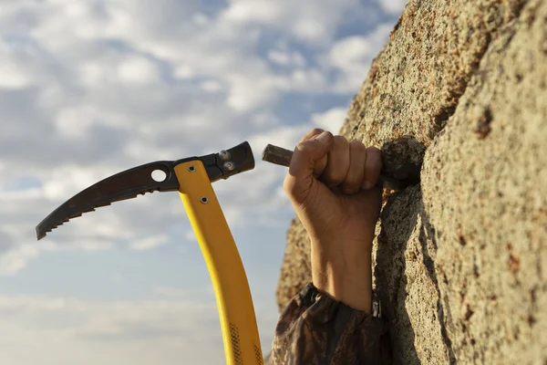 Hands rock-climber hammering in hook in rock — Stock Photo, Image