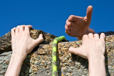 Rock climber reaching for helping-hand partner. clipart