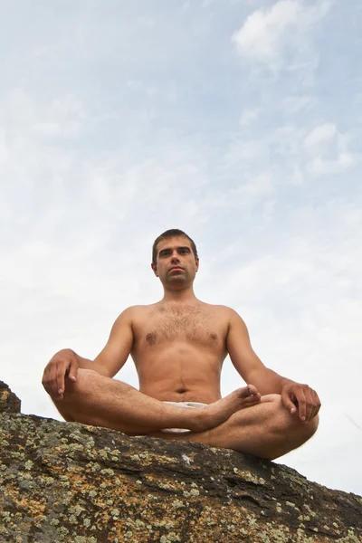 Jovem bonito fazendo ioga na pedra — Fotografia de Stock