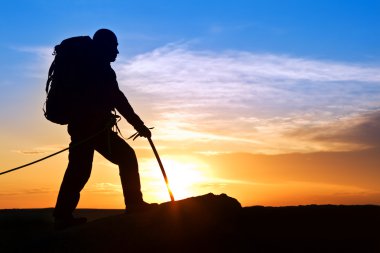 Silhouette of the rock-climber on background sunrising clipart