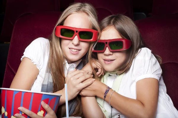 Zwei schöne Mädchen, die einen Film im Kino ansehen — Stockfoto
