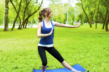 Yeşil çimlerde yoga yapan kadın.