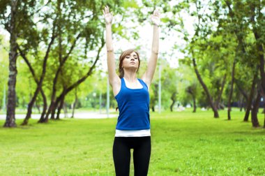 Yeşil çimlerde yoga yapan kadın.