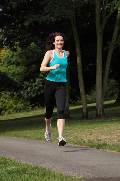 Hermosa mujer joven en forma corriendo en el parque — Foto de Stock