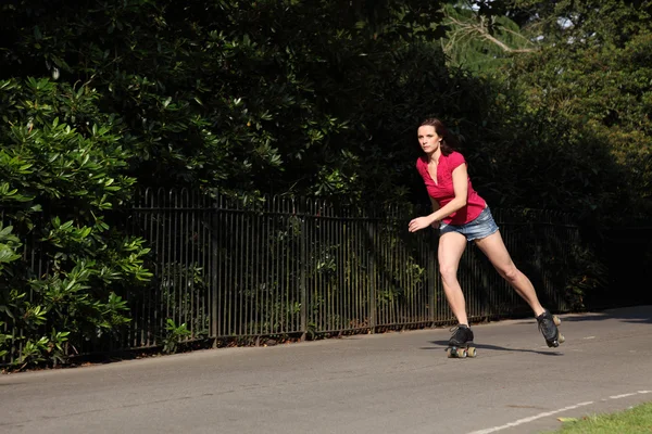 Mooi lang viervoetige meisje rolschaatsen in park — Stockfoto