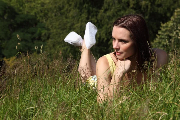 美しい若い女性は田舎草で横になっています。 — ストック写真
