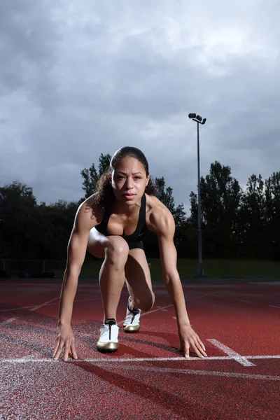 Женщина-атлет в стартовой позиции на треке — стоковое фото