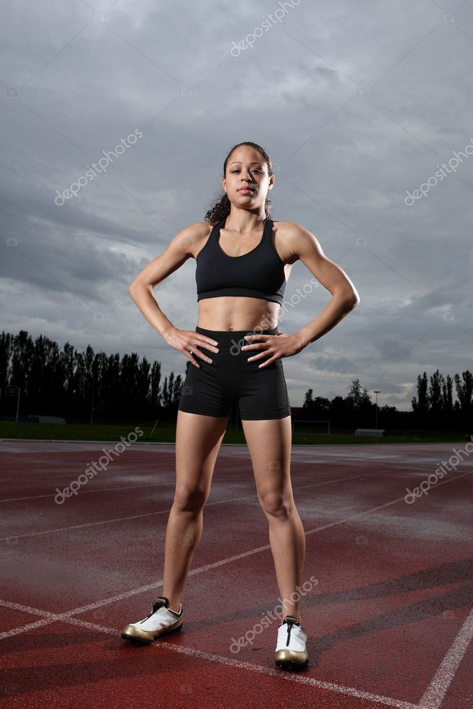 Woman athlete in fitness attire standing on running track with
