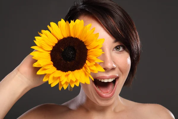 Schöne glückliche junge Mädchen Sonnenblume auf ihr Gesicht — Stockfoto