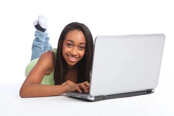 Linda chica adolescente africana en línea utilizando el ordenador portátil Imágenes de stock libres de derechos