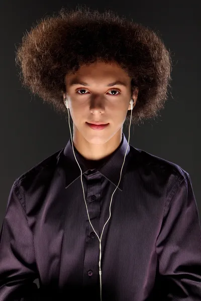Jovem usa tampões de ouvido de música e cabelo afro grande — Fotografia de Stock