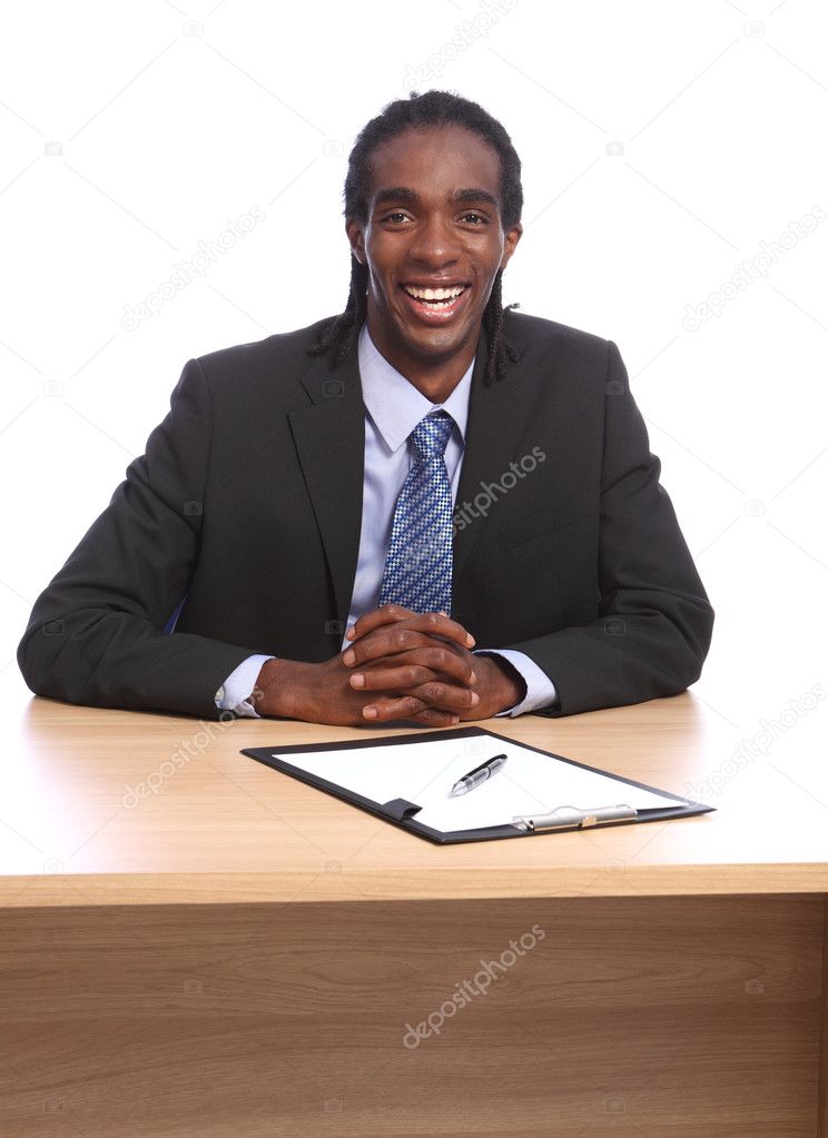 Happy young black businessman sits to office desk