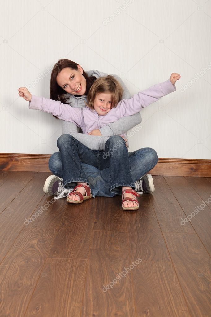 Young mother and daughter sitting on floor at home