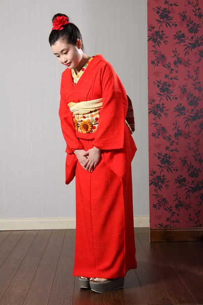 Oriental model in red Japanese kimono bowing — Stock Photo, Image