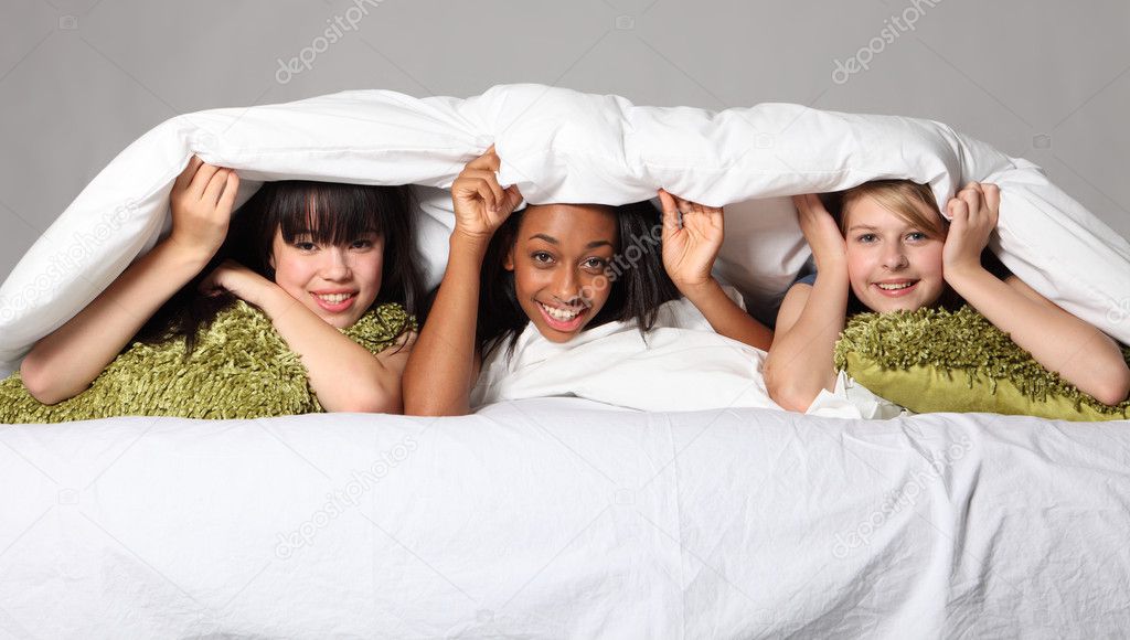 Sleepover party fun teenage girls laughing in bed