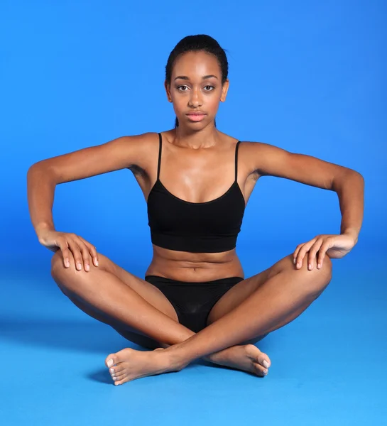 Atletische Afrikaanse fitness vrouw zit cross legged — Stockfoto