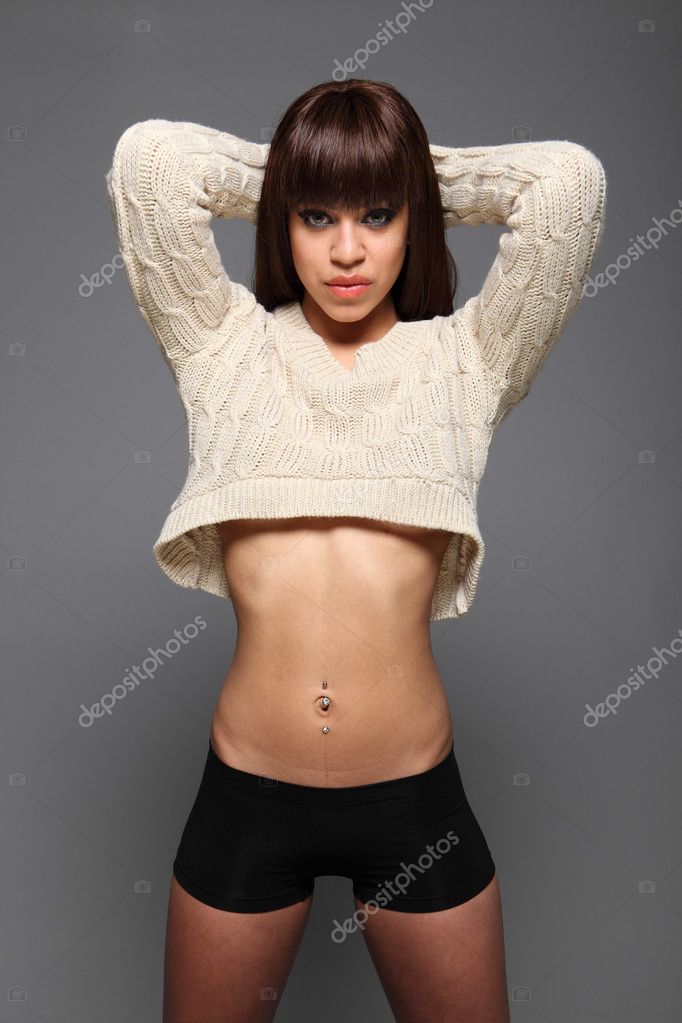 A Young Topless Girl With Small Boobs And An Flat Stomach And In Jeans,  Standing In Front Of The Camera With Her Hands On The Legs. Stock Photo,  Picture and Royalty Free