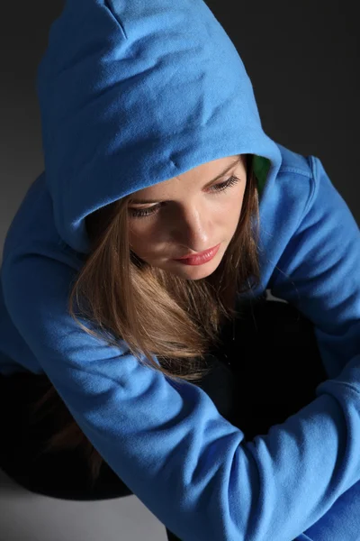 Ledsen tonåring flicka ensam på golvet i blå hoodie — Stockfoto