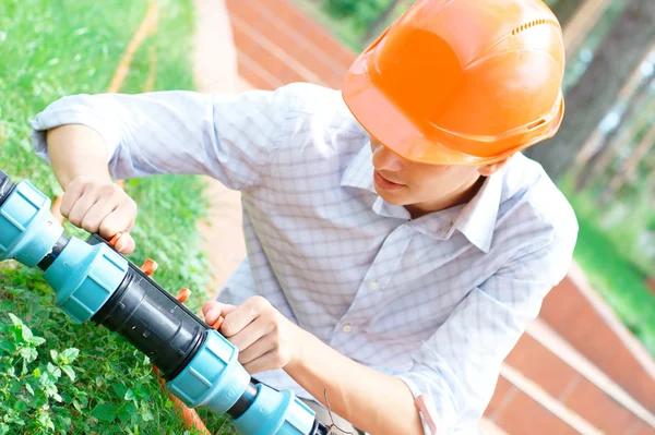 Young worker repairing a pipe — Stock Photo, Image
