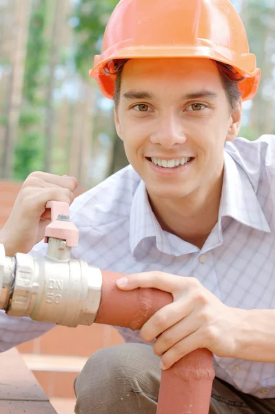 Trabalhador sorridente reparando um tubo Imagens De Bancos De Imagens Sem Royalties