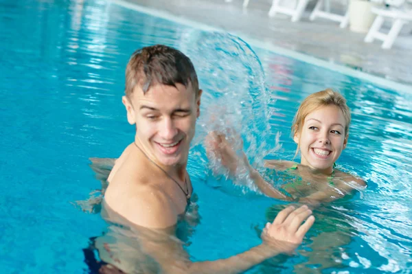 Splashing casal na piscina Fotografias De Stock Royalty-Free