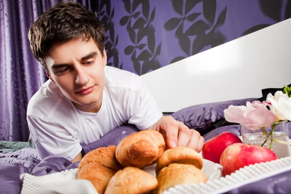 躺在床上吃早餐的男性 — 图库照片