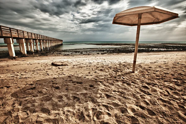 Paraguas y muelle en la playa — Foto de Stock