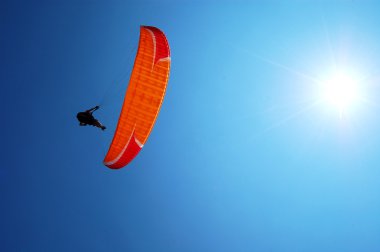 Paragliders fly with the sun behind clipart