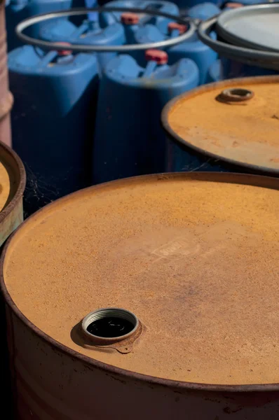 Old colored oil barrels and blue canisters — Stock Photo, Image