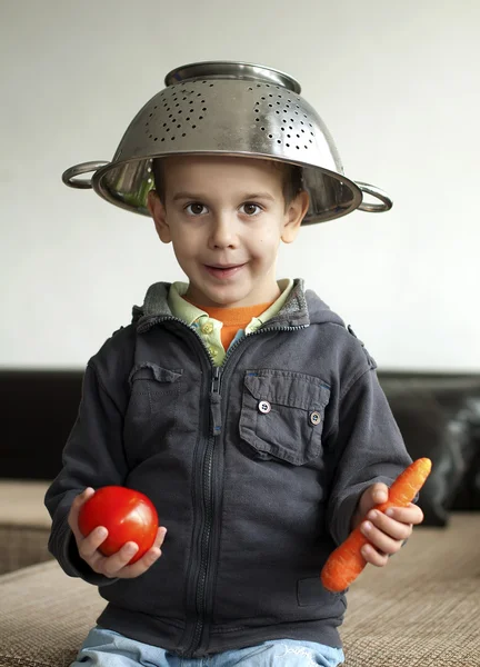 Jongen met tomaat en wortel in hand — Stockfoto
